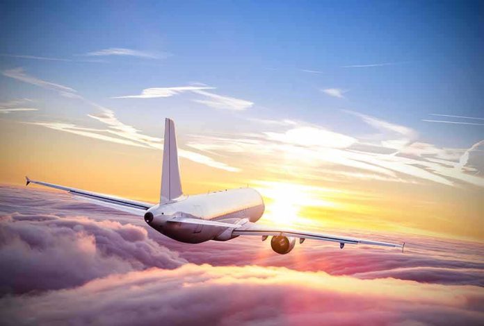 shutterstock_553131187 Airplane flying above clouds at sunrise