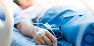 Patient hand with IV line resting on hospital bed