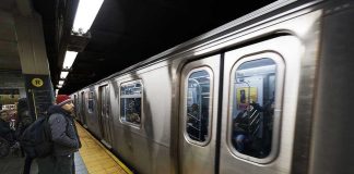 Subway train at platform with passengers inside and man waiting