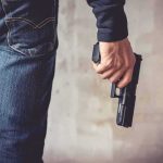 person holding a handgun by their side