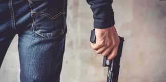 person holding a handgun by their side