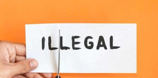 hands cutting paper with the word illegal