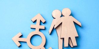 Wooden transgender symbol and two human figures on blue background