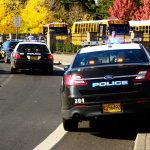 Knife Chaos Inside Manchester Classroom Police cars with flashing lights near school buses on a city street