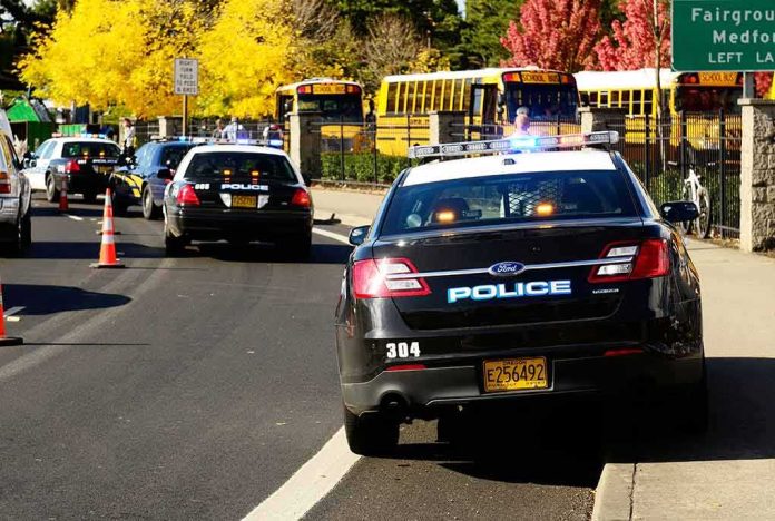 Police cars with flashing lights near school buses on a city street
