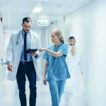 The Assisted Death Her Daughters Tried to Stop Doctor and nurse walking in a hospital corridor reviewing a tablet
