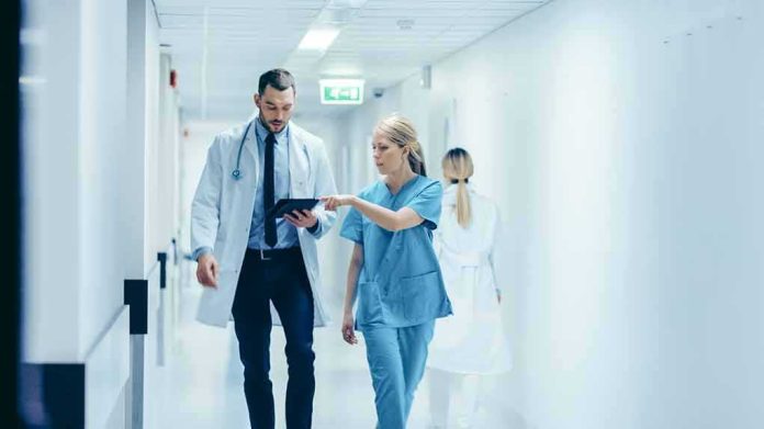 Doctor and nurse walking in a hospital corridor reviewing a tablet