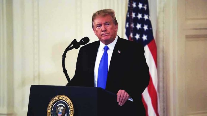 man at podium with microphone and US flag