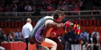 Caraun Reid in red wrestling an opponent during a college match