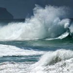 Hurricane Polo Could Become A Major Storm Crashing ocean waves against the shore under a cloudy sky