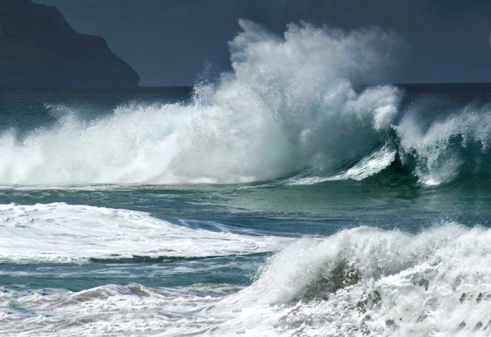 shutterstock_13625515 Crashing ocean waves against the shore under a cloudy sky