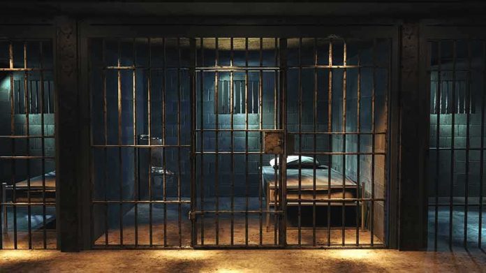 shutterstock_1427252378 Prison cell with metal bars and a single bed