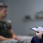 Young Men Face An Unexpected Workplace Risk Therapist taking notes while man sits on couch