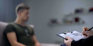 Therapist taking notes while man sits on couch