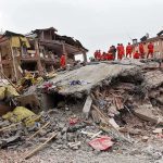 Rescues Race As Death Toll Shifts Rescue workers in orange uniforms on a collapsed building site after an earthquake