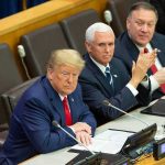 three men in suits seated at a conference table