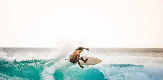 surfer carving on a turquoise wave at sunset