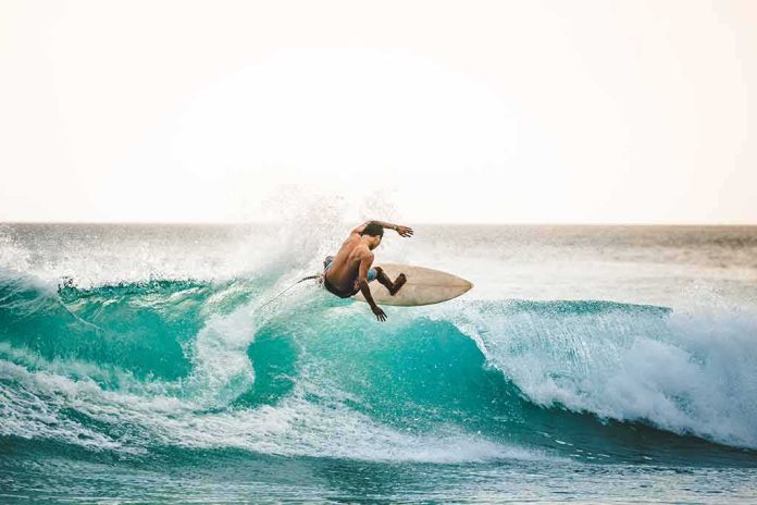 shutterstock_1591974517 surfer carving on a turquoise wave at sunset
