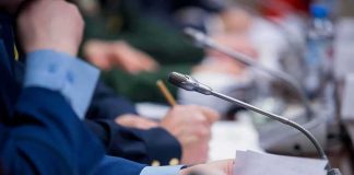 Conference microphone on table with hands holding documents