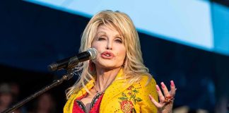 Dolly Parton performing on stage in a yellow floral jacket