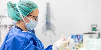medical professional in blue gown putting on sterile gloves