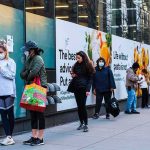 City Groceries, Zero Checks — What’s Stopping Abuse? People wearing masks line up outside a store on a city sidewalk