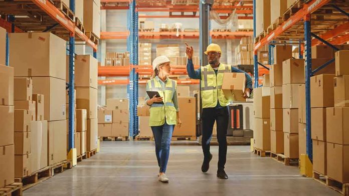 shutterstock_1848611116 Warehouse workers walking among shelves with boxes