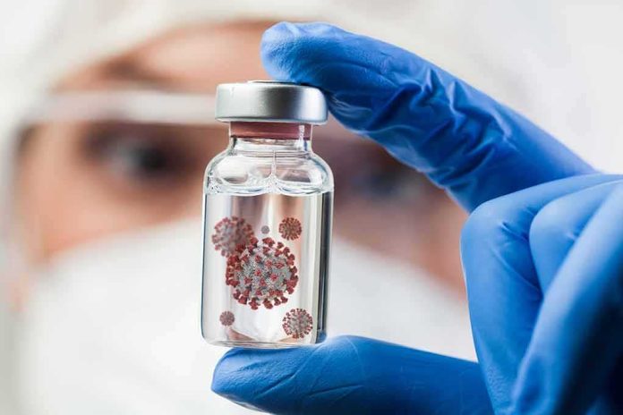 shutterstock_1882992490 Gloved hand holding a small vial in a lab