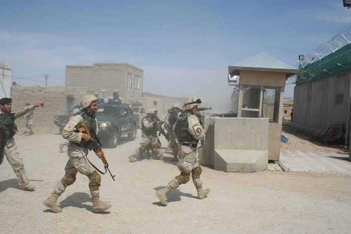 shutterstock_1931171405-1 Soldiers in desert uniforms run past a checkpoint amid dust