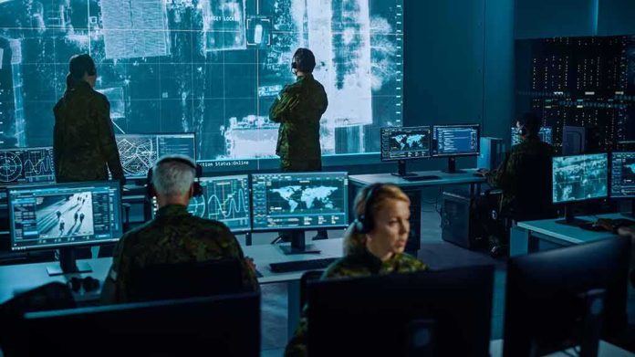 shutterstock_1936992886-1 Military analysts monitor data on multiple screens in a command center