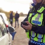 Officer’s Death Reignites Early Release Debate Police officer using a smartphone during a roadside stop