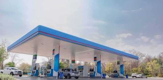 Gas station canopy with multiple fuel pumps and parked cars
