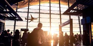 Airport terminal crowd at sunset with airplane silhouette outside