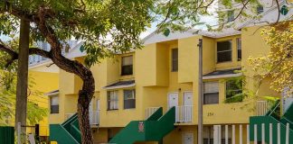 Yellow apartment building with green staircases and parked cars