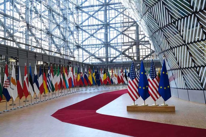 shutterstock_2134763595 Row of national flags in a modern glass atrium with red carpet and EU and US flags upfront