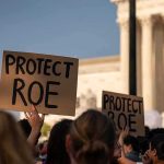 Protesters holding signs at a demonstration outside a courthouse