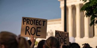 Protesters holding signs at a demonstration outside a courthouse