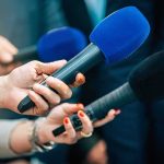 Racial Profiling Bombshell Derails Spy Drive Reporters holding colorful microphones