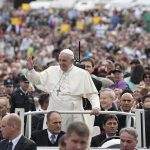 Francis waves from a vehicle amid a large crowd; Keith Allen and Andreas Hestler are also present