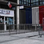 Media Shrug As Marchers Demand Justice Police station entrance with barriers and French flag colors