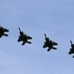 Four fighter jets flying in formation against a clear sky