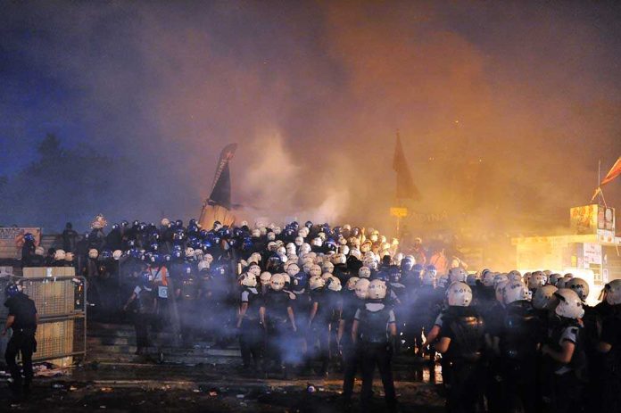 shutterstock_234178564 Riot police gather amid smoke at night