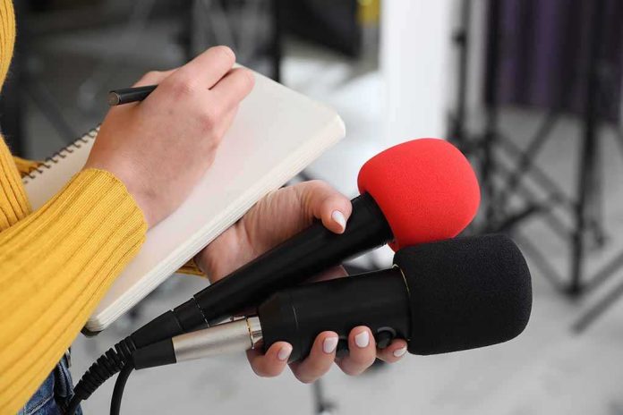 shutterstock_2431198207 Journalist holding two microphones while writing in a notebook