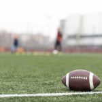 American football on a turf field near the sideline