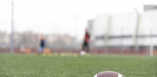 American football on a turf field near the sideline