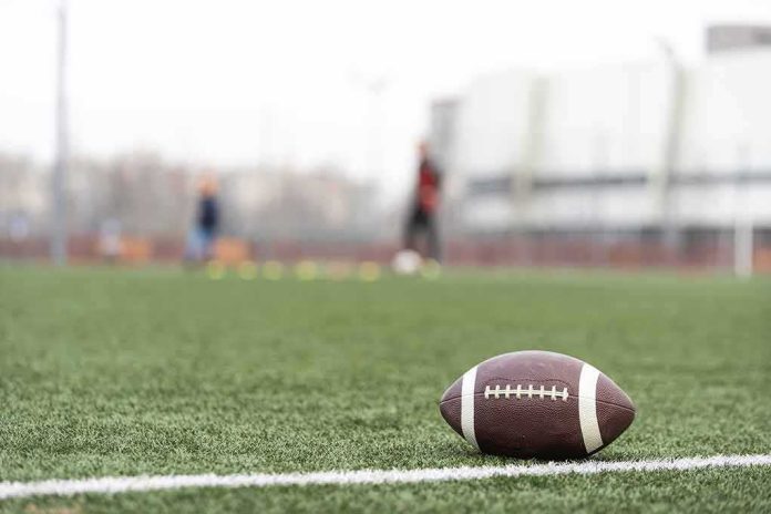 American football on a turf field near the sideline