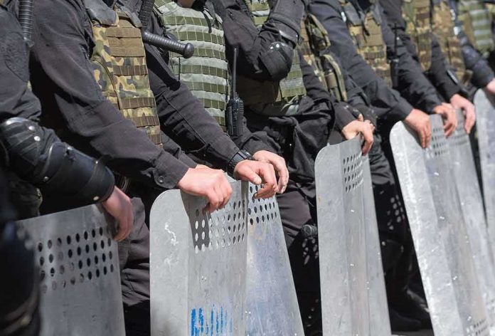 shutterstock_460081330 Riot police line holding metal shields