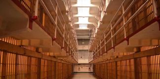 Prison cellblock corridor with barred cells and upper walkways
