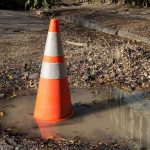 Raging Timber Fire — 16 Miles Dark Traffic cone in a water-filled pothole on a damaged road
