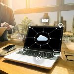 AI Overlords Replace Jobs—Not Quite Yet! Laptop on desk showing cloud network icons
